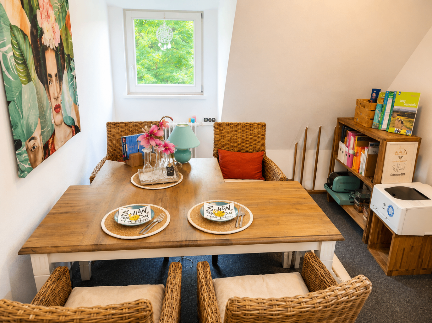 Heller Essbereich mit Frida-Kahlo-Wandbild und Rattanstühlen